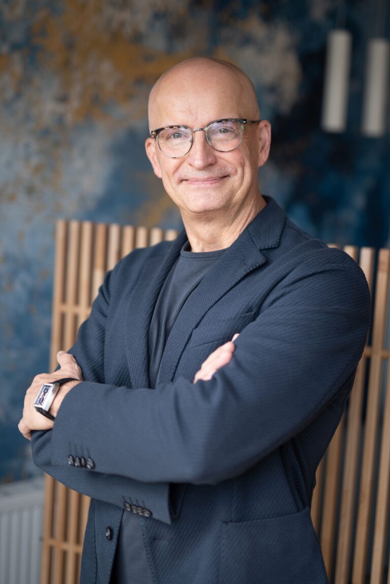 Dr Jacek Taczyński – psychiatra Psychiatra Bydgoszcz – Dr Jacek Taczyński w okularach i marynarce, z założonymi rękami